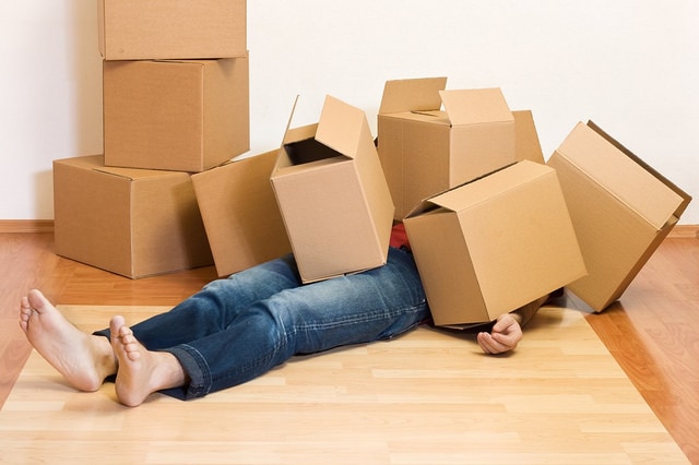 A person laying on the ground underneath moving boxes