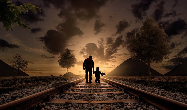 man and a child on a railroad at sunset