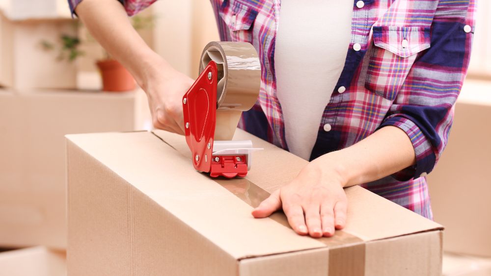 Woman using packing tape on a moving box
