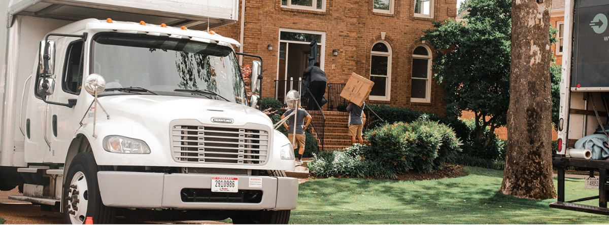 moving truck outside a house and crew helping move boxes