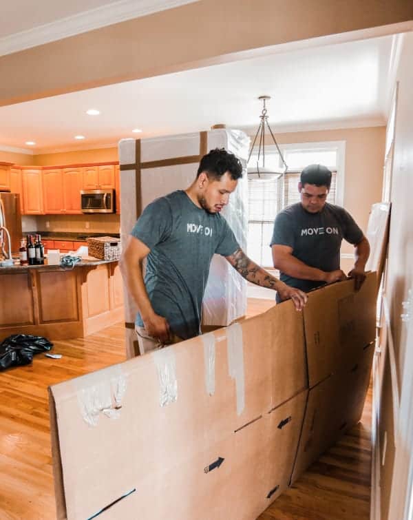 Move On movers unpacking a cardboard box in a kitchen